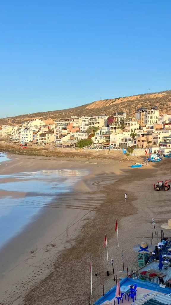 Taghazout as the sun is rising over the town, with a tractor moving fishing boats into the sea.