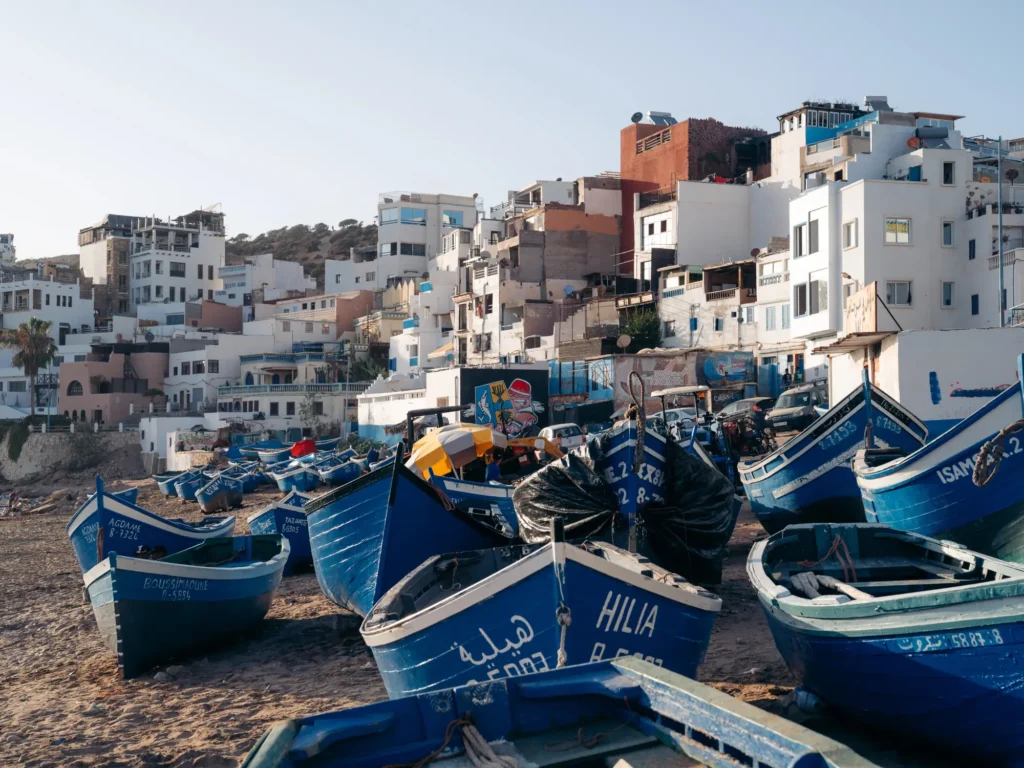 Taghazout buildings with lots of blue fishing boats on the beach.