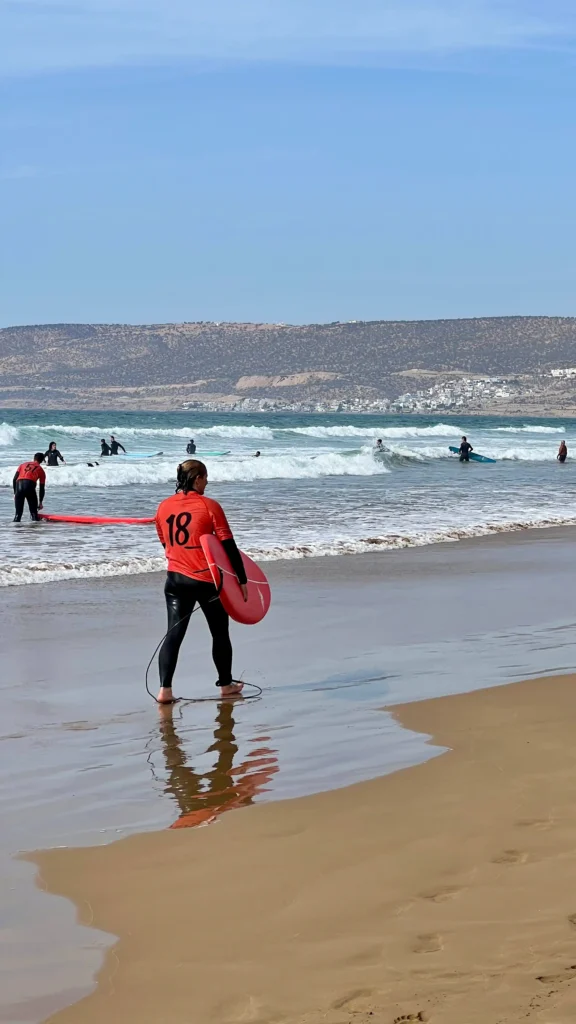 Surfers walking with their boards and in the sea at Imourane beach.