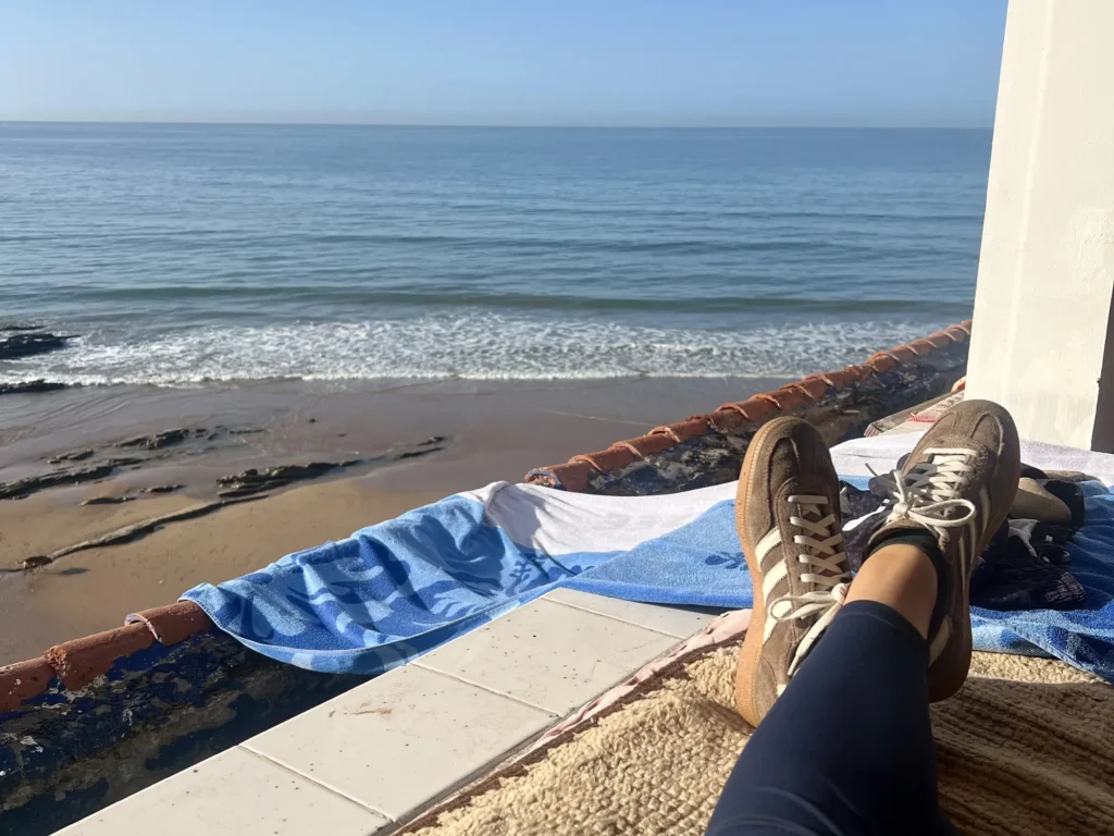 Sitting, relaxing with crossed legs looking over the ocean as waves roll in.