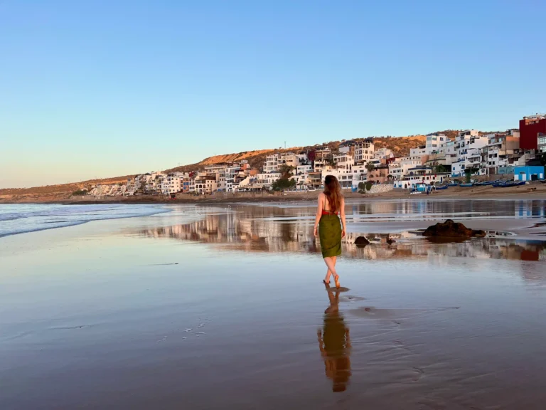 Girl walking along Taghazout beach as the sun rises.