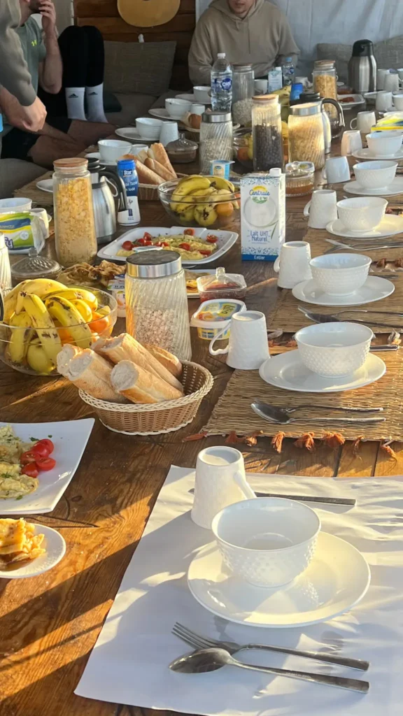 Family-style dinner at a Taghazout surf camp, with one big table and all the table settings laid on and breakfast is served on the table.