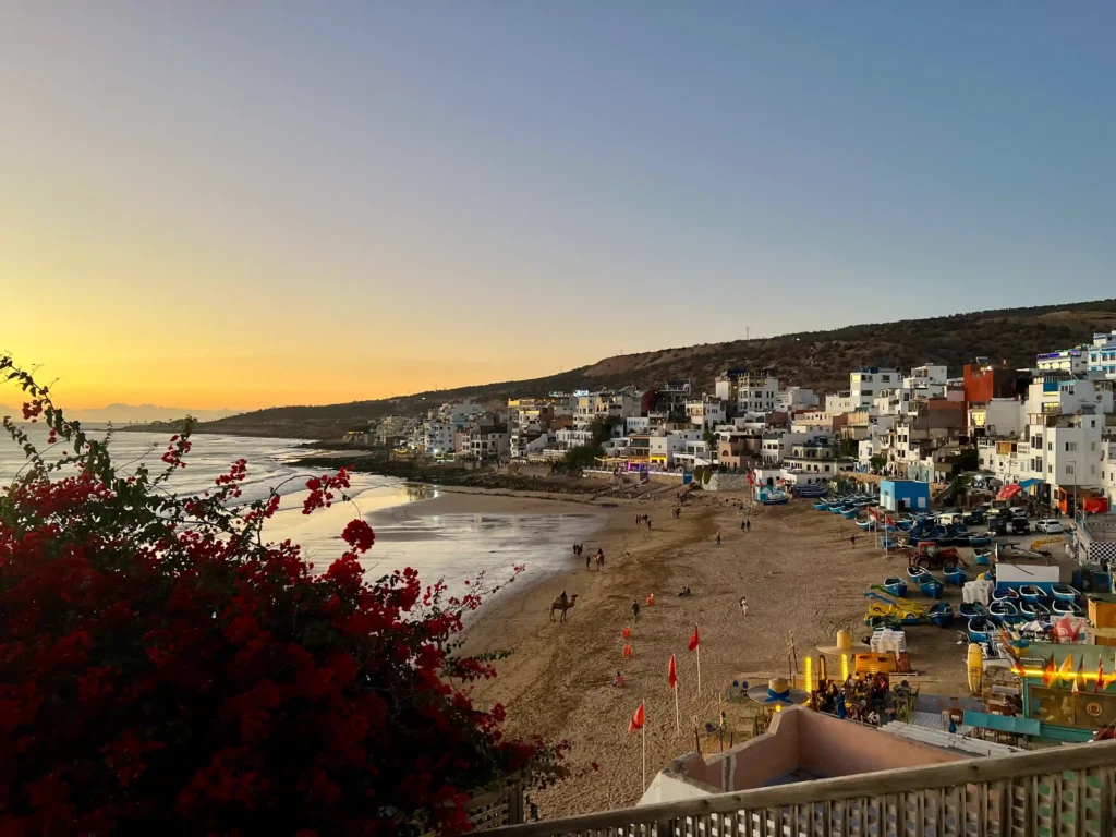 Taghazout in Morocco as the sun is setting with lights in the town.